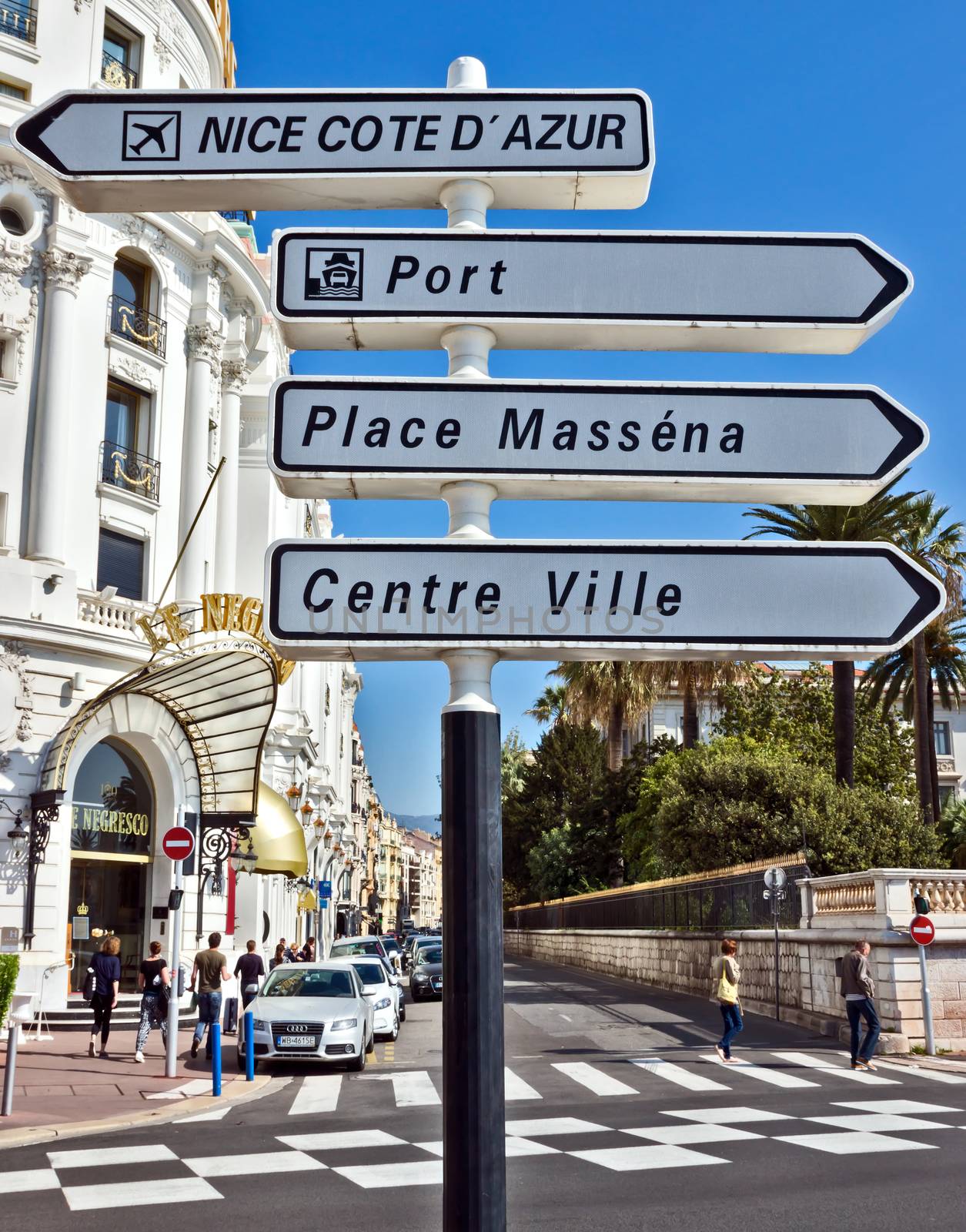 NICE, FRANCE - MAY 4: Road signpost against luxury Hotel Negresco on May 4, 2013 in Nice, France. Hotel Negresco is the famous luxury hotel on the Promenade des Anglais in Nice, a symbol of the Cote d'Azur.

Nice, France - May 4, 2013: Road signpost against luxury Hotel Negresco in Nice, French Riviera. Hotel Negresco is the famous luxury hotel on the Promenade des Anglais in Nice, a symbol of the Cote d'Azur. People are walking by street.