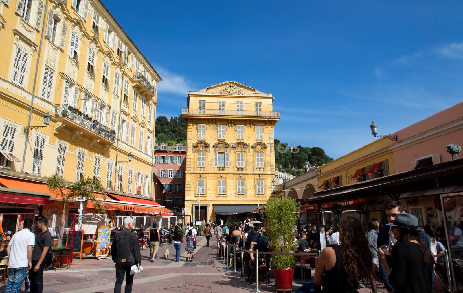 NICE, FRANCE - MAY 4: Old building and a cafe in the Cours Saleya on May 4, 2013 in Nice, France. The Cours Saleya is a place of outdoor restaurants and a market. 

Nice, France - May 4, 2013: Old building and a cafe in the Cours Saleya. People are walking and relaxing.
The Cours Saleya is a place of outdoor restaurants, boutiques and a market. 