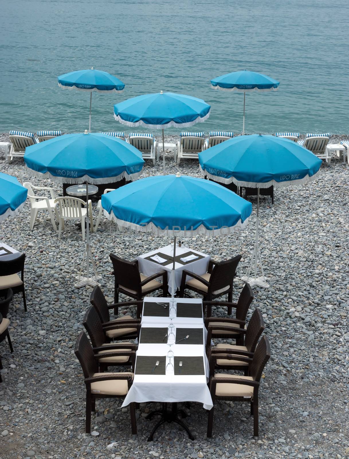 NICE, FRANCE - MAY 5: Beach and cafe with blue umbrellas near Promenade des Anglais on May 5, 2013 in Nice, France. There are many cafes and restaurants along the coast of the Côte d'Azur.

Nice, France - May 5, 2013: Beach and cafe with blue umbrellas near Promenade des Anglais in city of Nice, France. There are many cafes and restaurants along the coast of the Côte d'Azur.