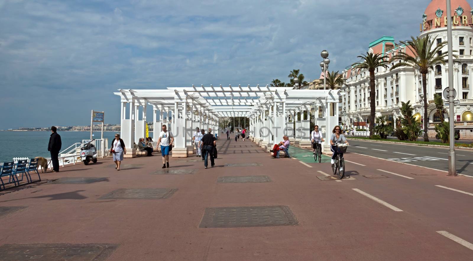 NICE, FRANCE - MAY 5: Promenade des Anglais on May 5, 2013 in Nice, France. It is a symbol of the Cote d'Azur and was built in 1830 at the expense of the British colony.

Nice, France - May 5, 2013 : Pedestrians walking on Promenade des Anglais. Promenade des Anglais is a symbol of the Cote d'Azur and was built in 1830 at the expense of the British colony.