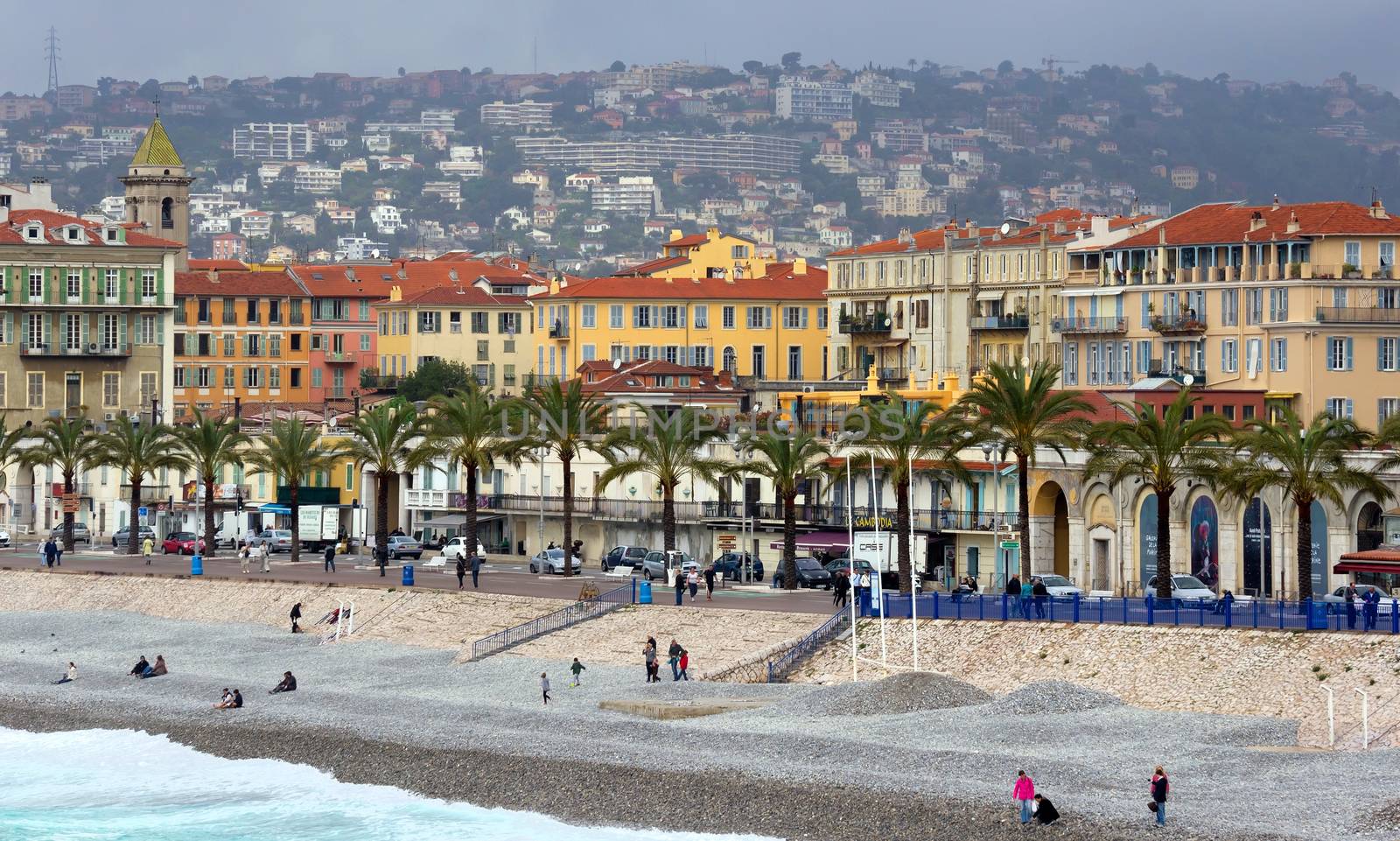 NICE, FRANCE - APRIL 27: Architecture along Promenade des Anglais on April 27, 2013 in Nice, France. It is a symbol of the Cote d'Azur and was built in 1830 at the expense of the British colony.

Nice, France - April 27, 2013: Architecture along Promenade des Anglais. People are resting. Promenade des Anglais is a symbol of the Cote d'Azur and was built in 1830 at the expense of the British colony. People are walking by Promenade and resting on the beach.