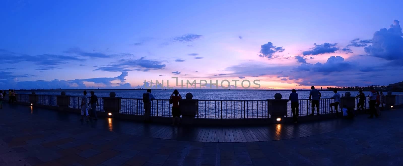 KAOHSIUNG, TAIWAN -- JULY 4, 2016: People enjoy the beautiful evening sky after sunset at a beach outside Kaohsiung Harbor.