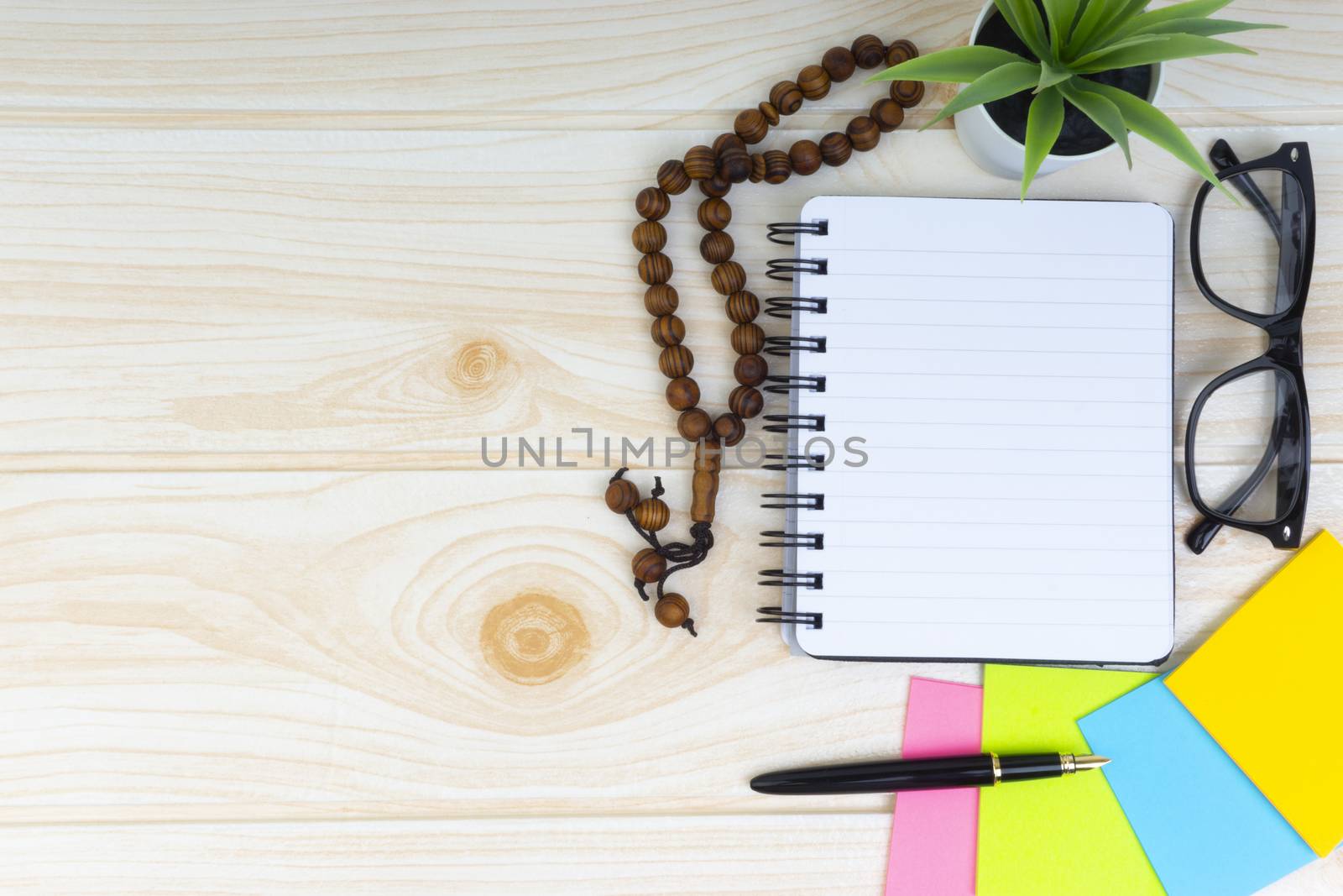 Flat lay view of workspace with Pen, spectacles, decoration flower, rosary and book.Copy Space, business and education concept. 