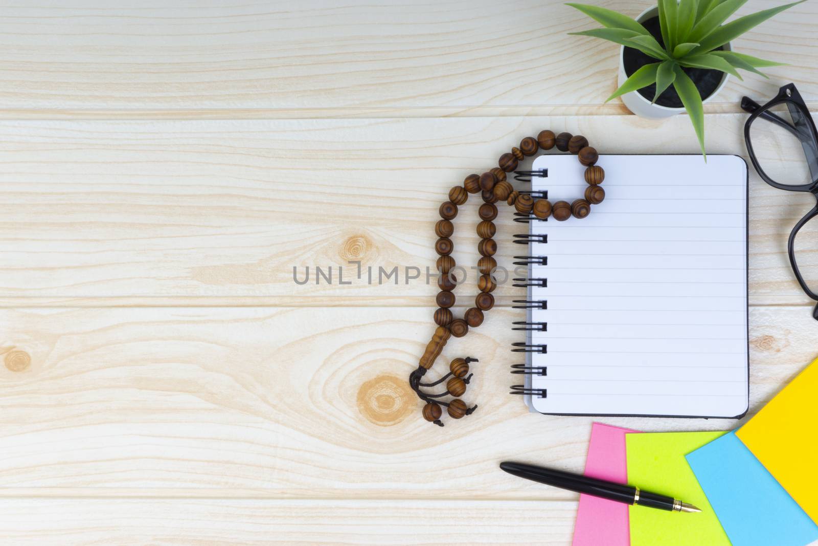 Flat lay view of workspace with Pen, spectacles, decoration flower, rosary and book.Copy Space, business and education concept. 