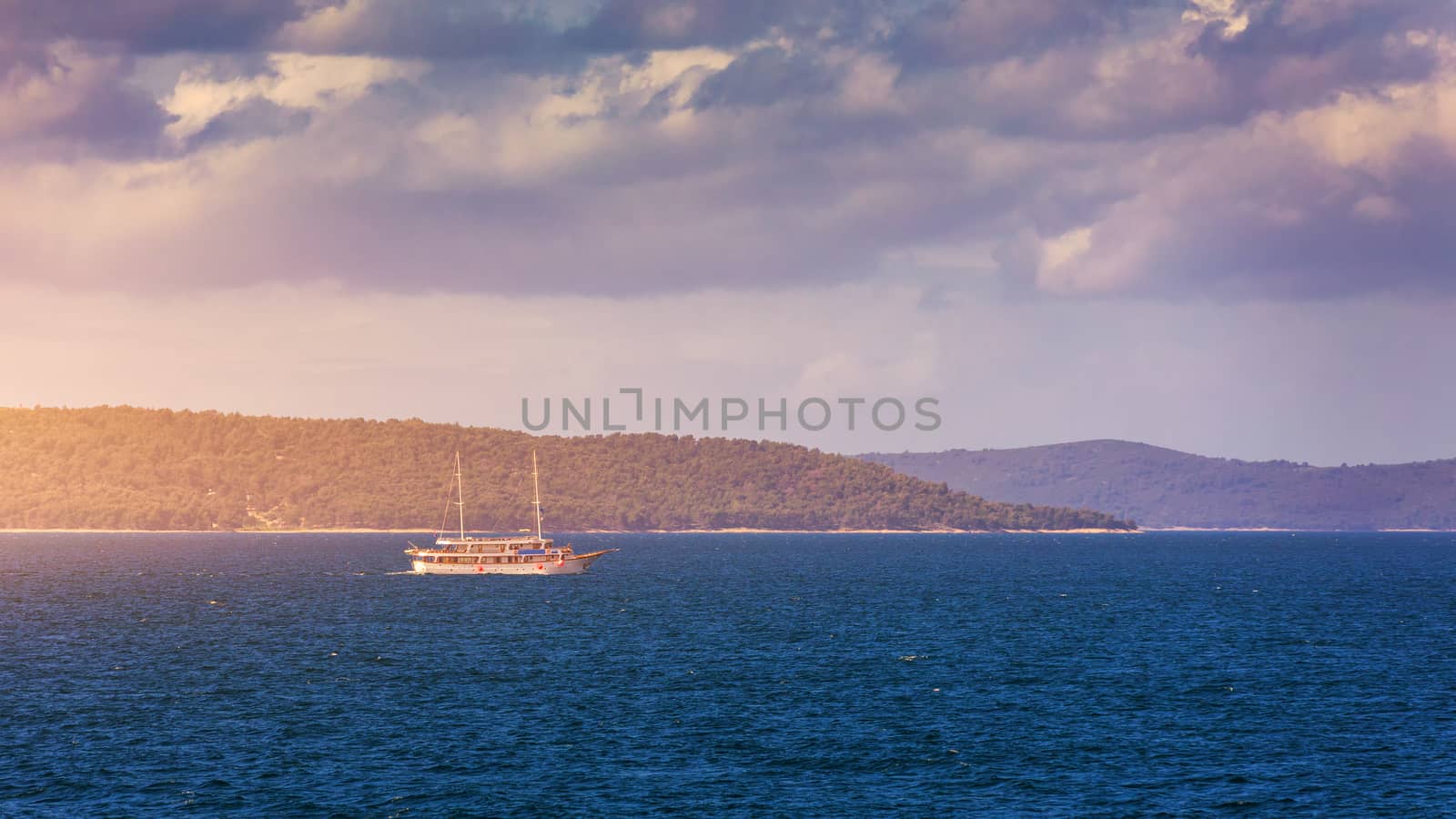 Sailboat in the sea in the evening sunlight with mountains background, luxury summer adventure, active vacation in Mediterranean sea, Croatia. Sailing ship luxury yacht with white sails in the Sea. 