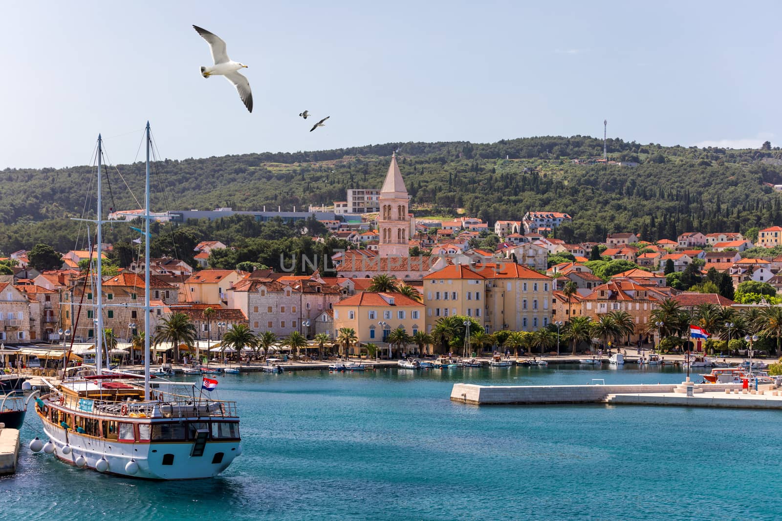 Supetar city in Brac island, Croatia. View from the sea. Picturesque scenic view on Supetar on Brac island, Croatia. Panoramic view on harbor of town Supetar from the side of sea. Brac, Croatia.