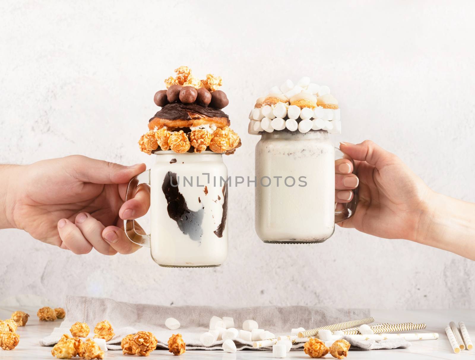 Friends hands clanging mason jars with extreme milkshakes on a party by Desperada