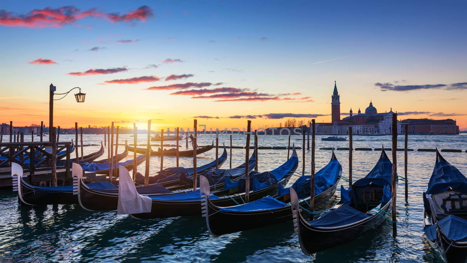 Venice with famous gondolas at sunrise, Italy. Gondolas in lagoon of Venice on sunrise, Italy. Venice with gondolas on Grand Canal against San Giorgio Maggiore church.