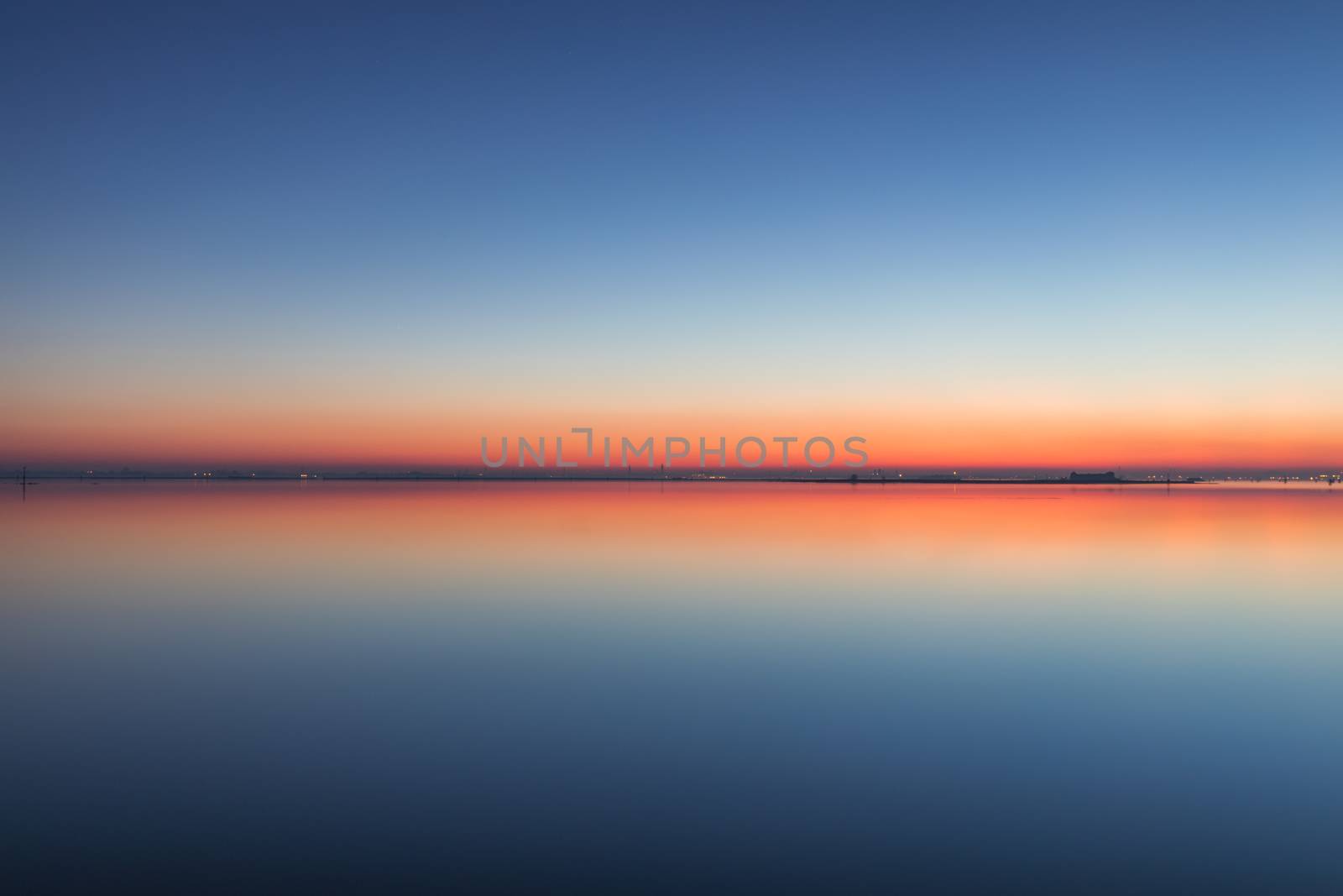 Mirroring sky in the water at twilight. Summer night picture of the surface of a calm lake mirroring the sky