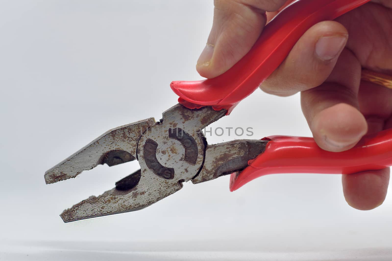 Old used iron cutting pliers tongs isolated in hand on white background by rkbalaji