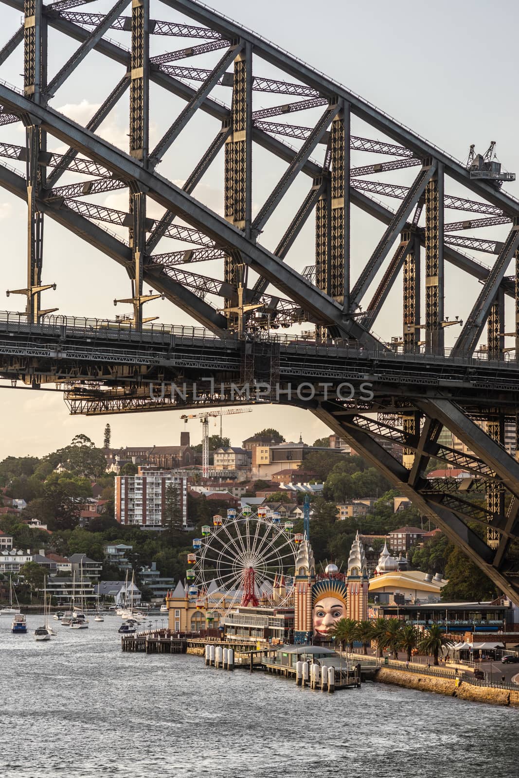 Sydney, Australia - February 12, 2019: closeup of Harbour bridge north side landing during sunset with Kirribilli neighborhood and Luna Park. Boats on water. Portrait.