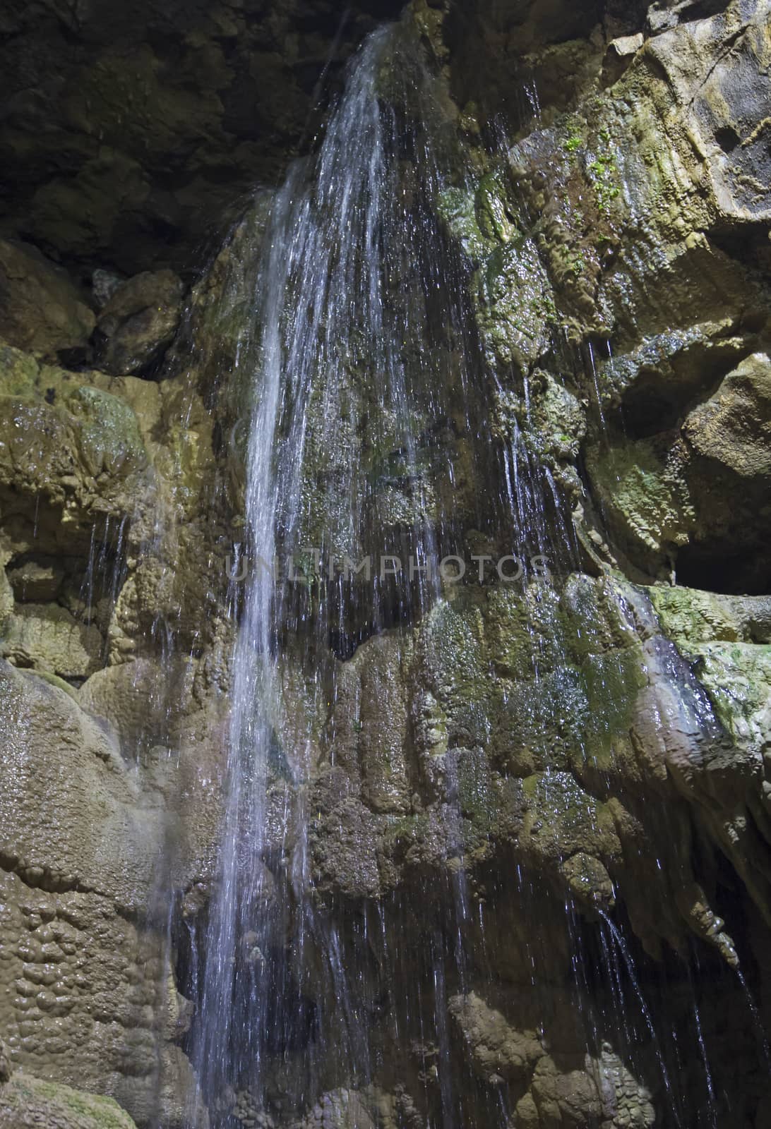 Closeup detail of geological rock formations in underground subterranean limestone cave cavern with waterfall