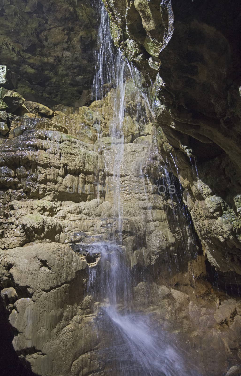 Closeup detail of geological rock formations in underground subterranean limestone cave cavern with waterfall