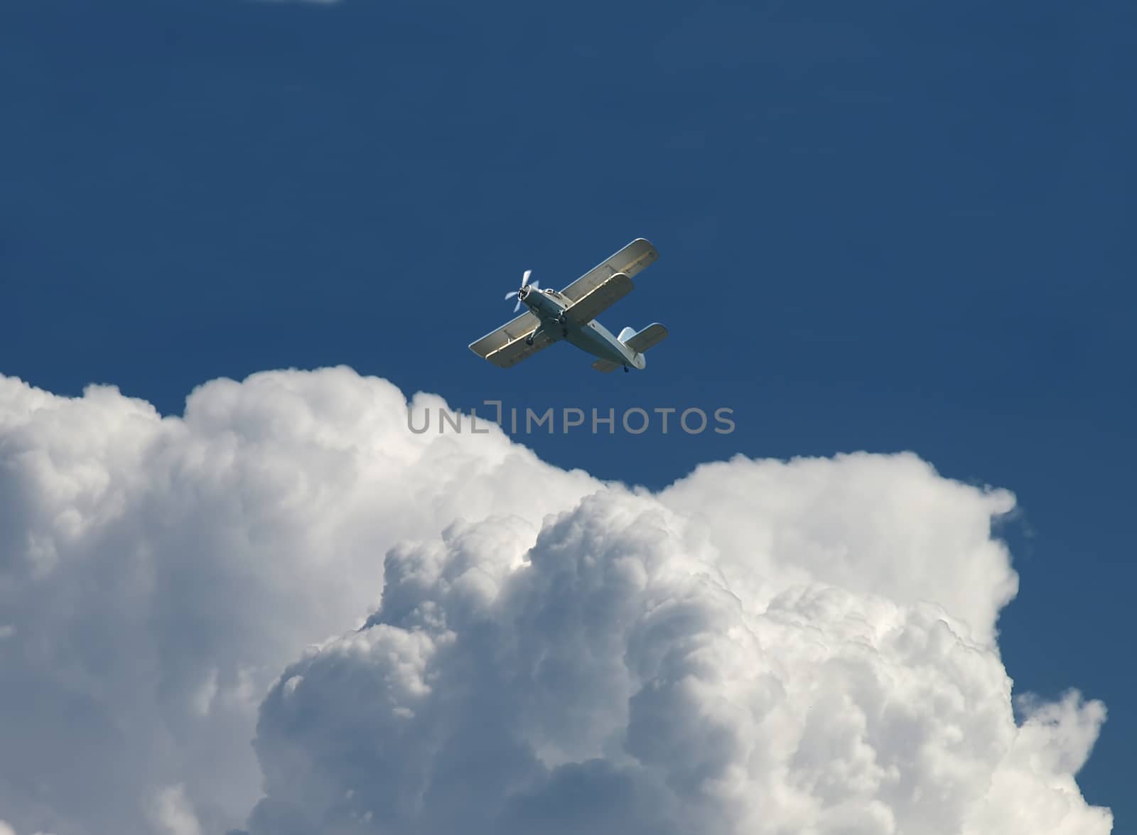 Blue sky with clouds and plane flying away. 