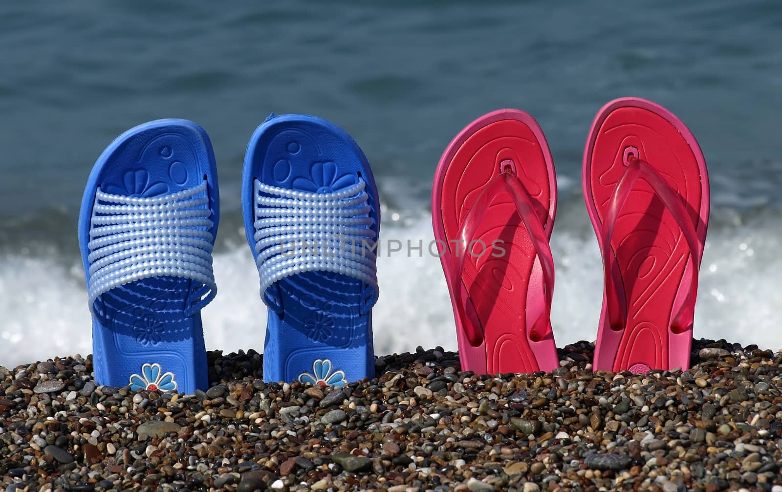 Blue and red flip-flop sandals on beach shore