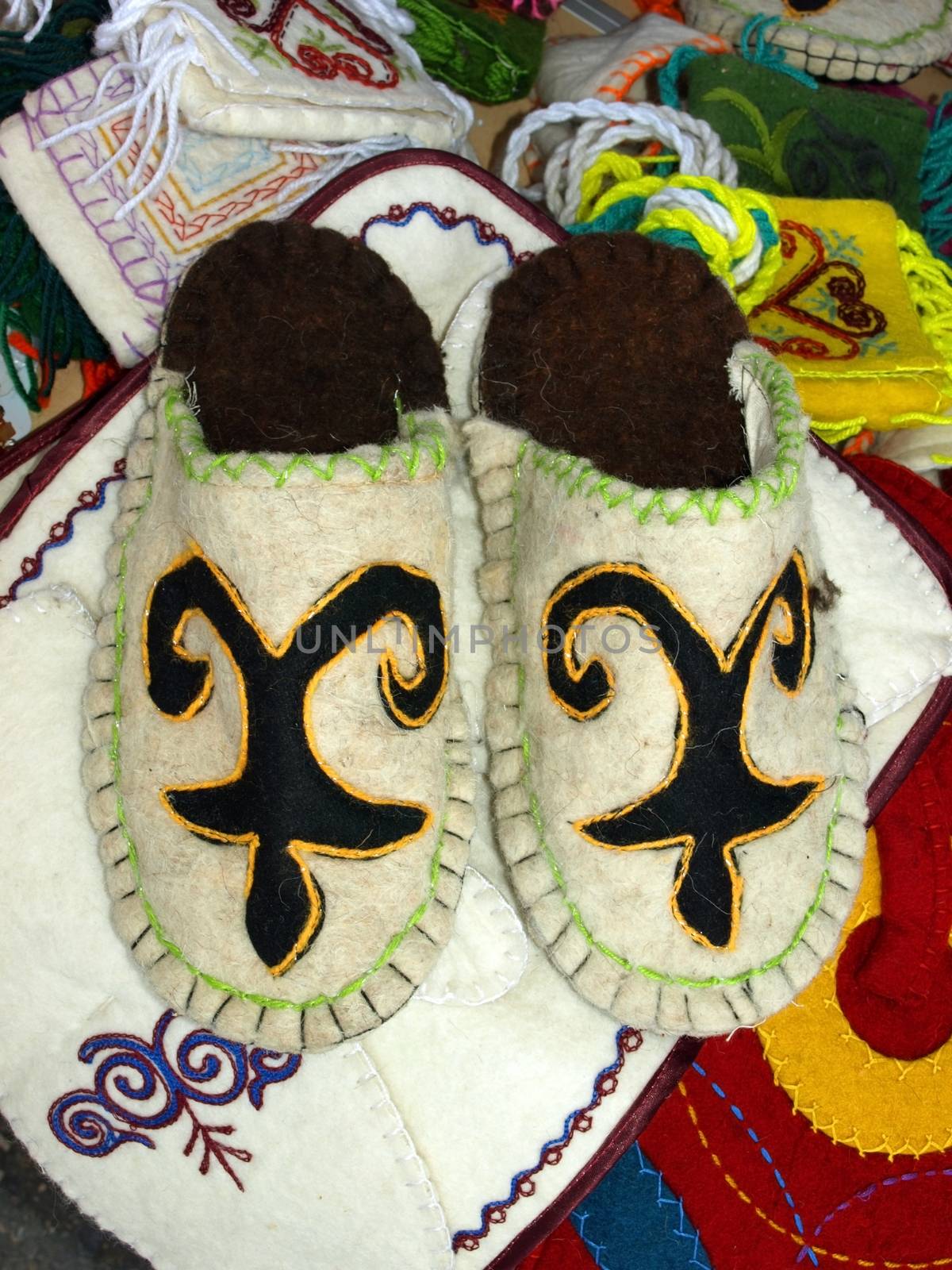 Kazakh national handicraft slippers over colored background.