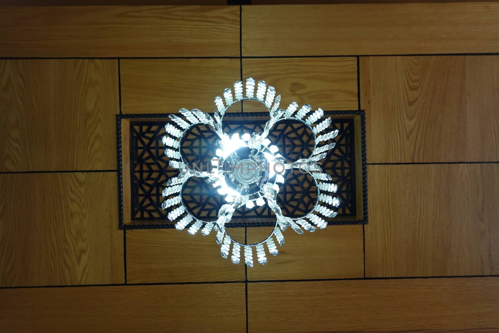 a beautiful cristal light decor on a wooden ceiling.