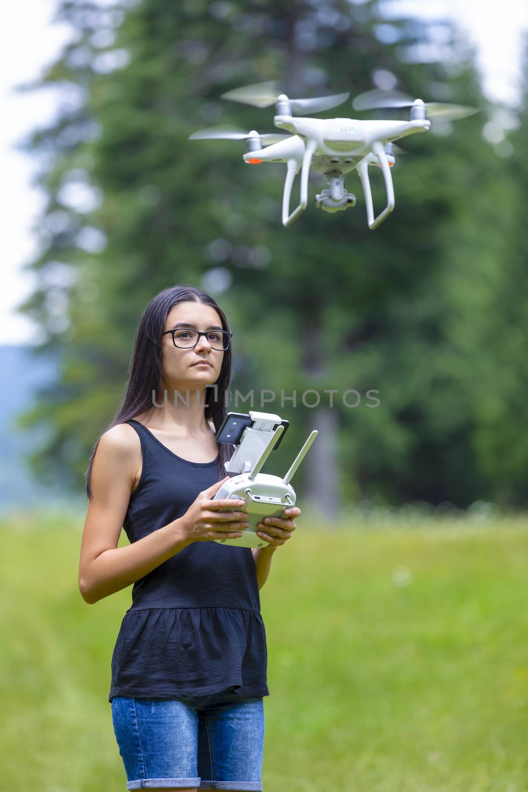 Teenage girl controlling drone with remote control in summer by manaemedia