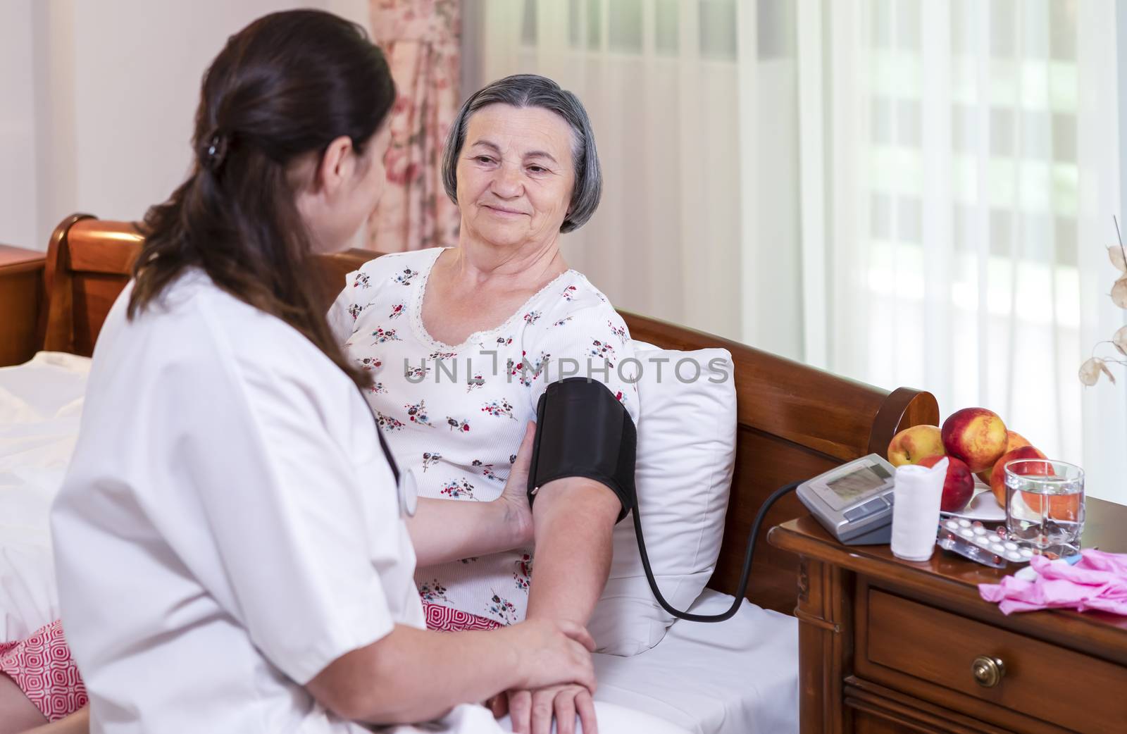 Female doctor checking blood pressure to senior woman by manaemedia