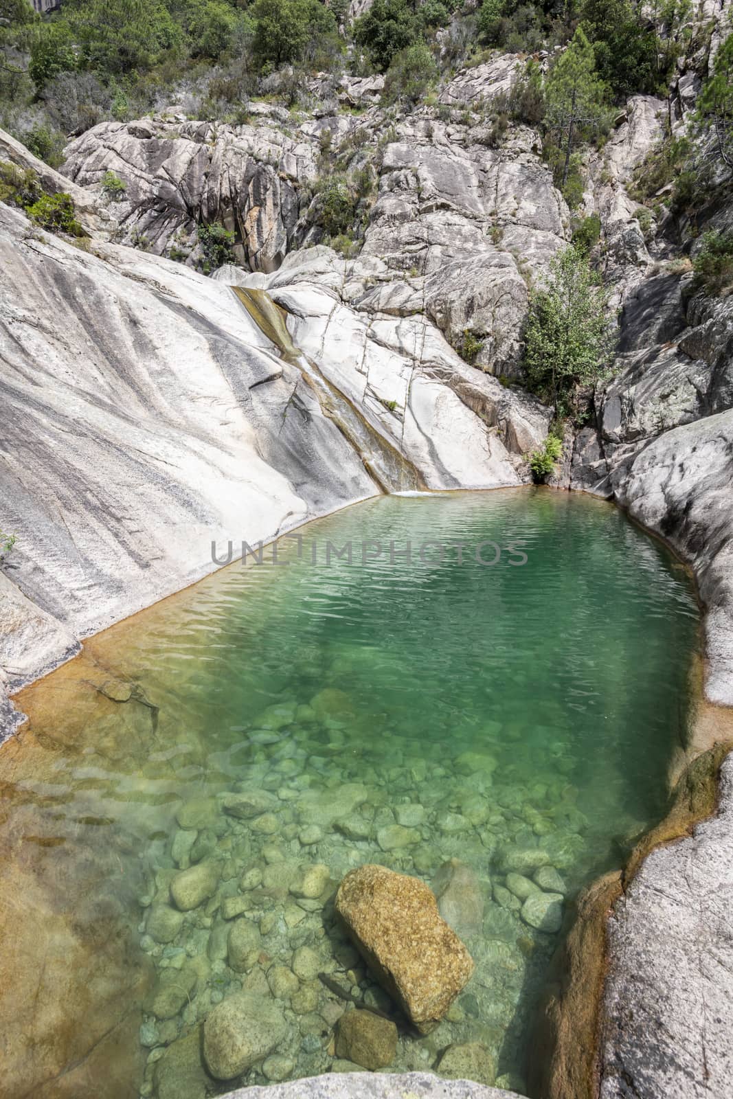 Waterfall and natural pool in Purcaraccia Canyon in Bavella during summer.  You will go through clear waters with amazing natural slides. Corsica, France