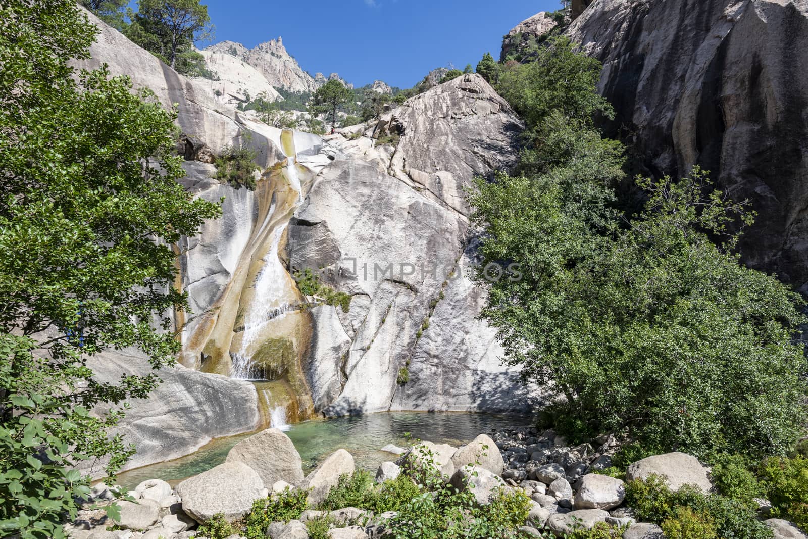 Waterfall and natural pool in the famous Purcaraccia Canyon in Bavella during summer, a tourist destination and attraction (for canyoning and hiking). Corsica, France