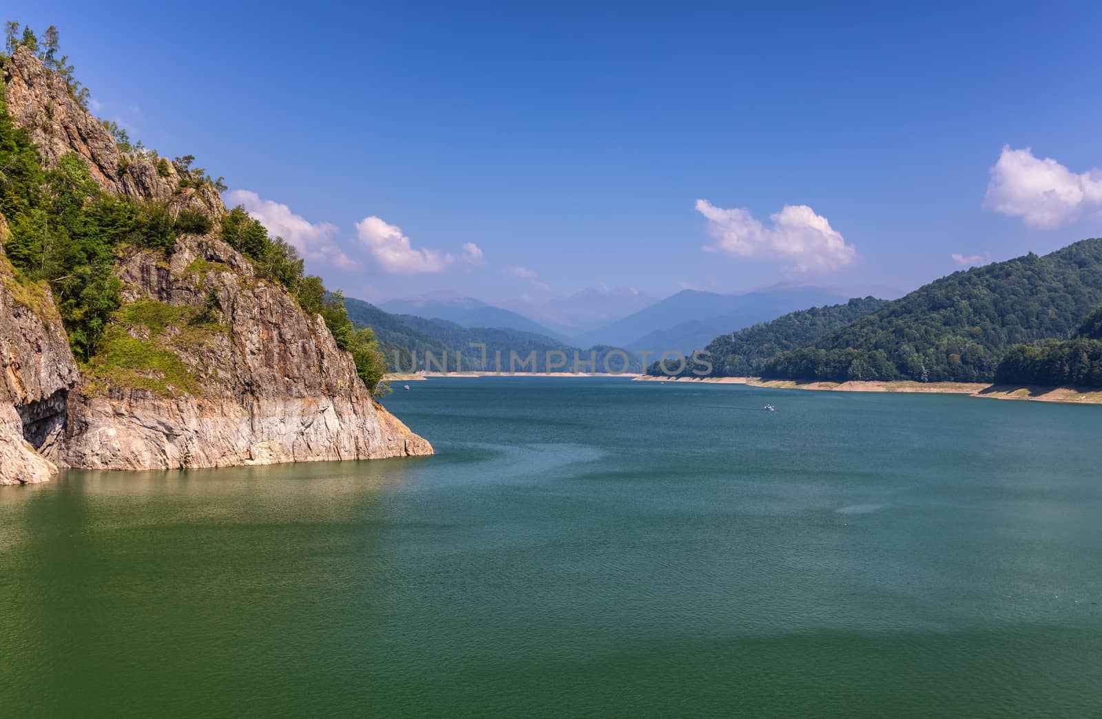 Summer scenery of Vidraru Dam and lake glowing in sunlight. Vidraru Dam, Romania. Carpathian Mountains, Fagaras ridge.