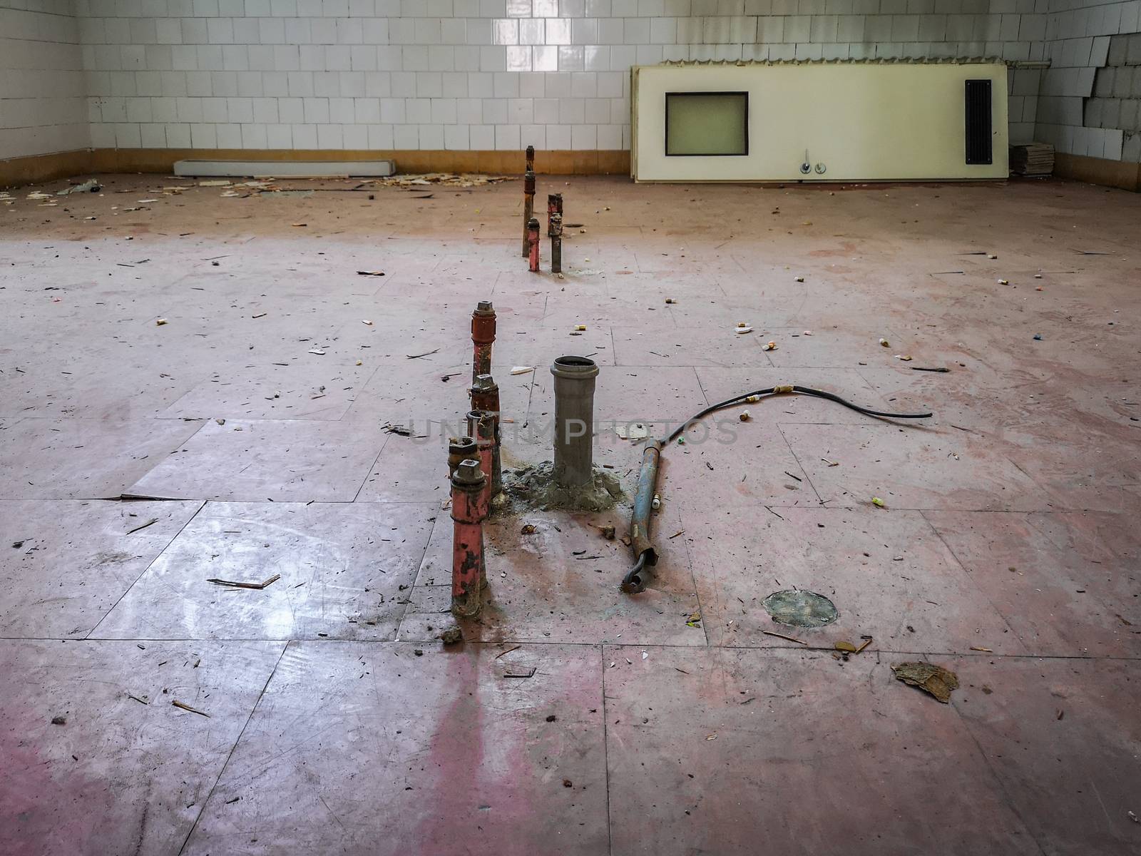 Water pipes in floor in old kitchen and doors leanded against the wall in old abandoned hospital by Wierzchu