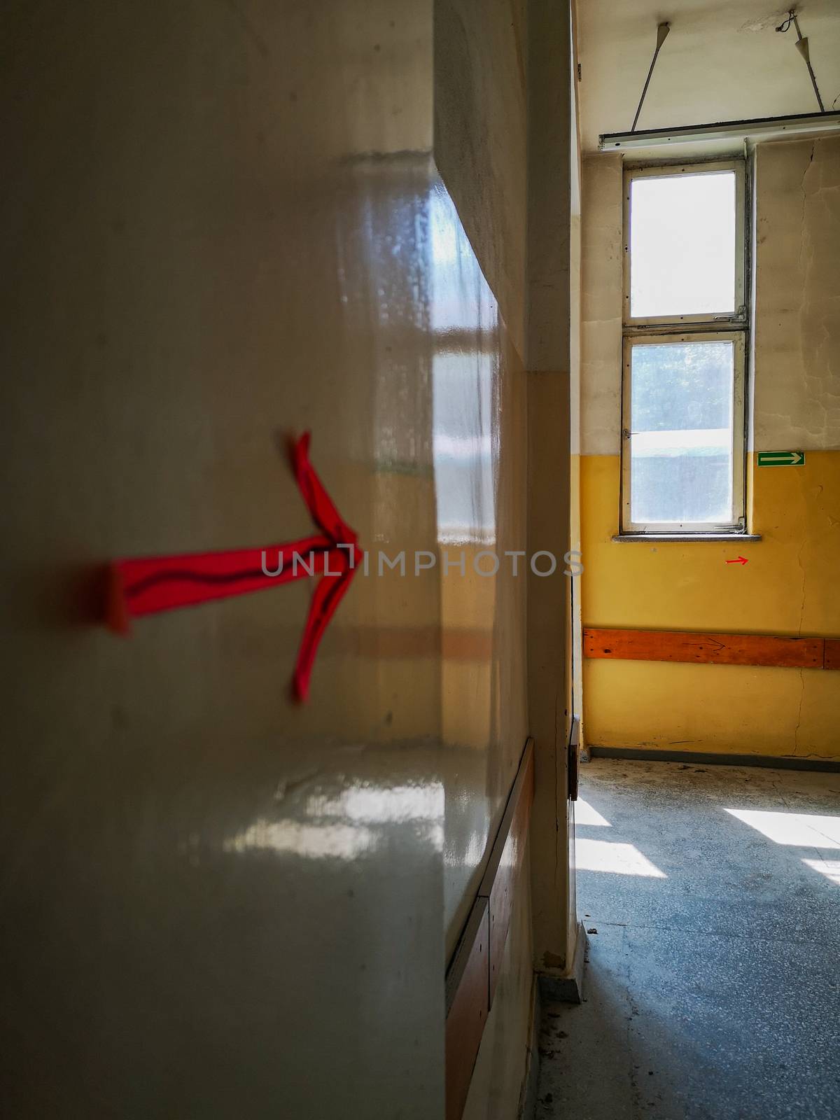 Paper arrows sticked to wall in old abandoned hospital corridor by Wierzchu