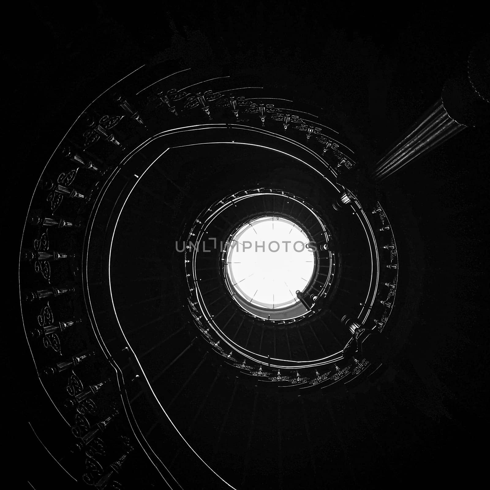 Upward look to Old spiral staircase with ornaments in tenement house  by Wierzchu