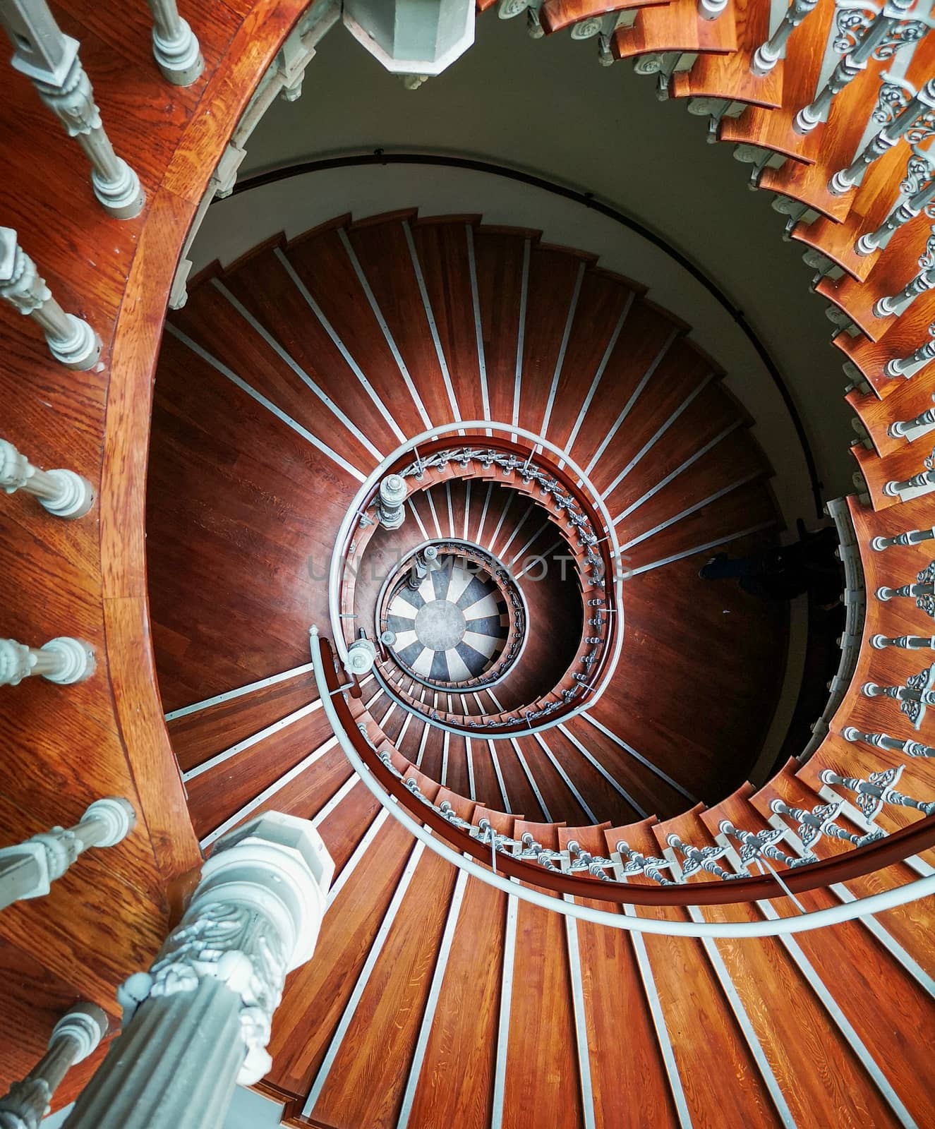 Top down look to Old spiral staircase with ornaments in tenement house  by Wierzchu