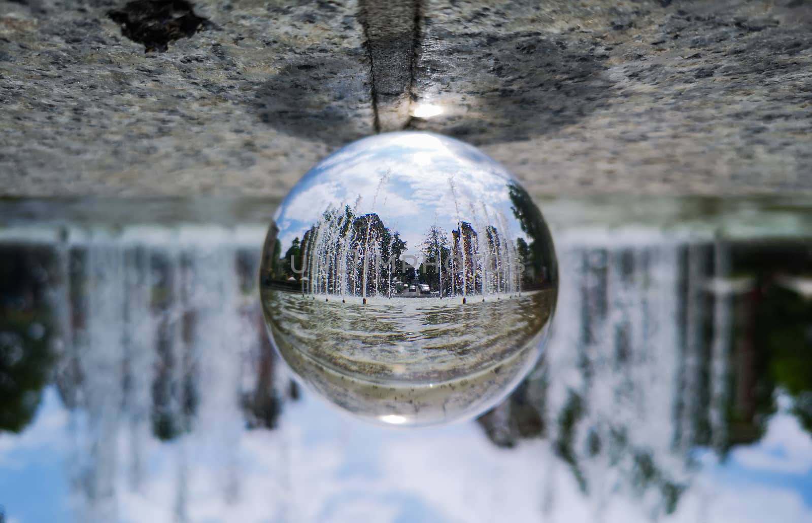 Big city fountain reflected in crystal glassy lens ball by Wierzchu