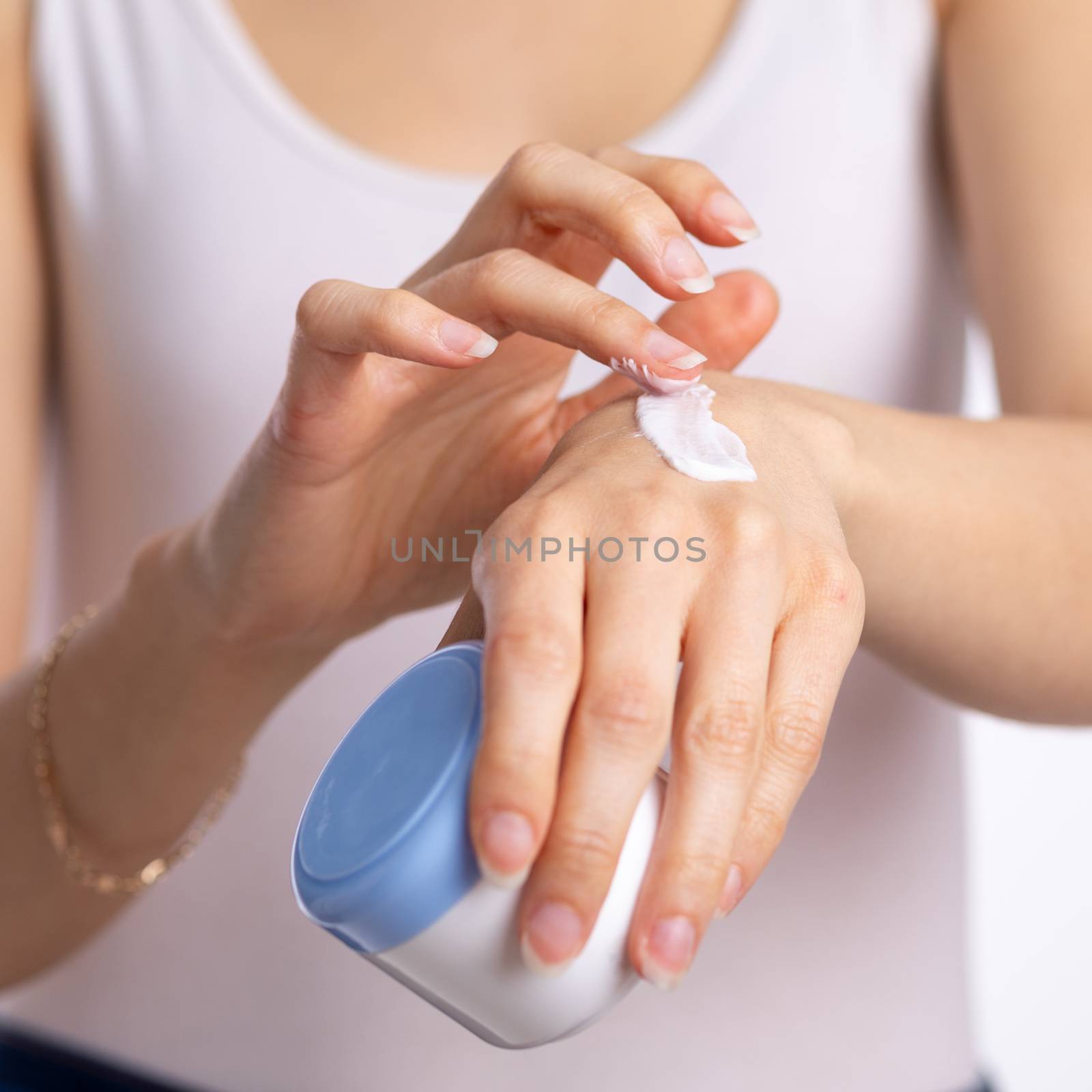 Woman applying hand cream to moisturize skin - stock photo by adamr