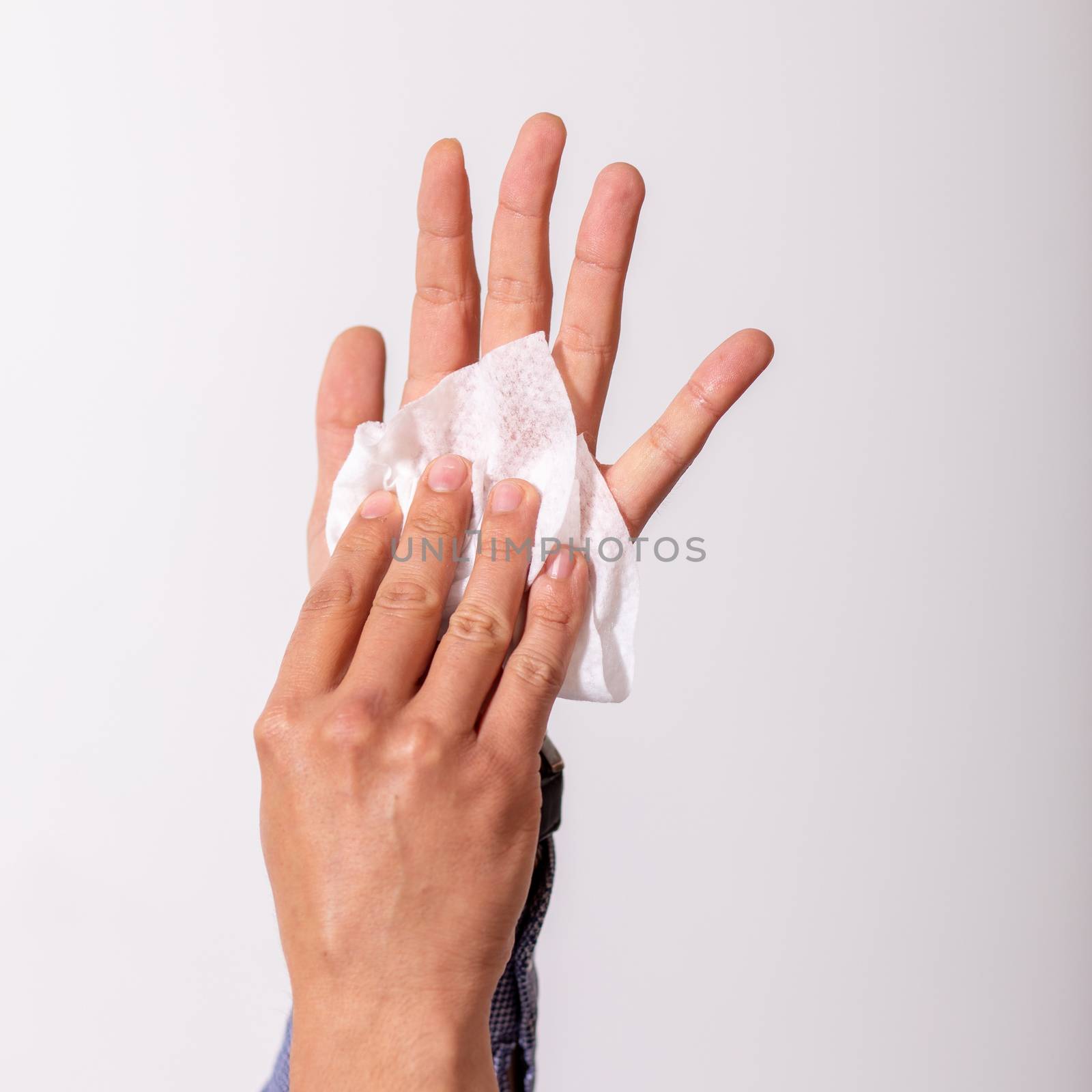 Young man cleaning hands with wet wipes