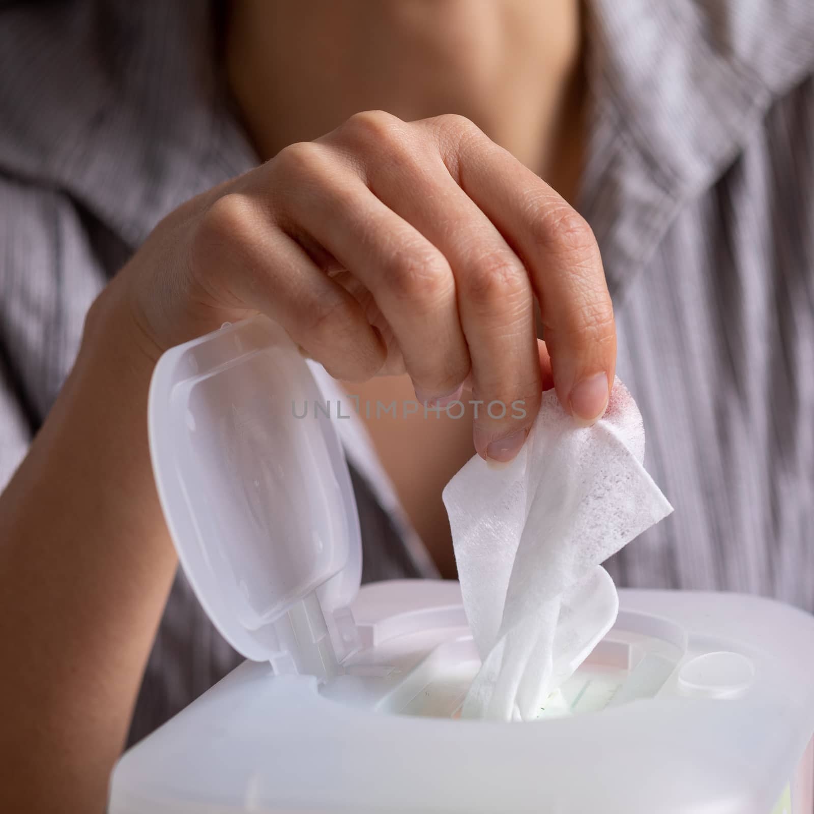 Wet wipes are universal an practical: woman hand take one wipe from big plastic box package for cleaning, home, indoor