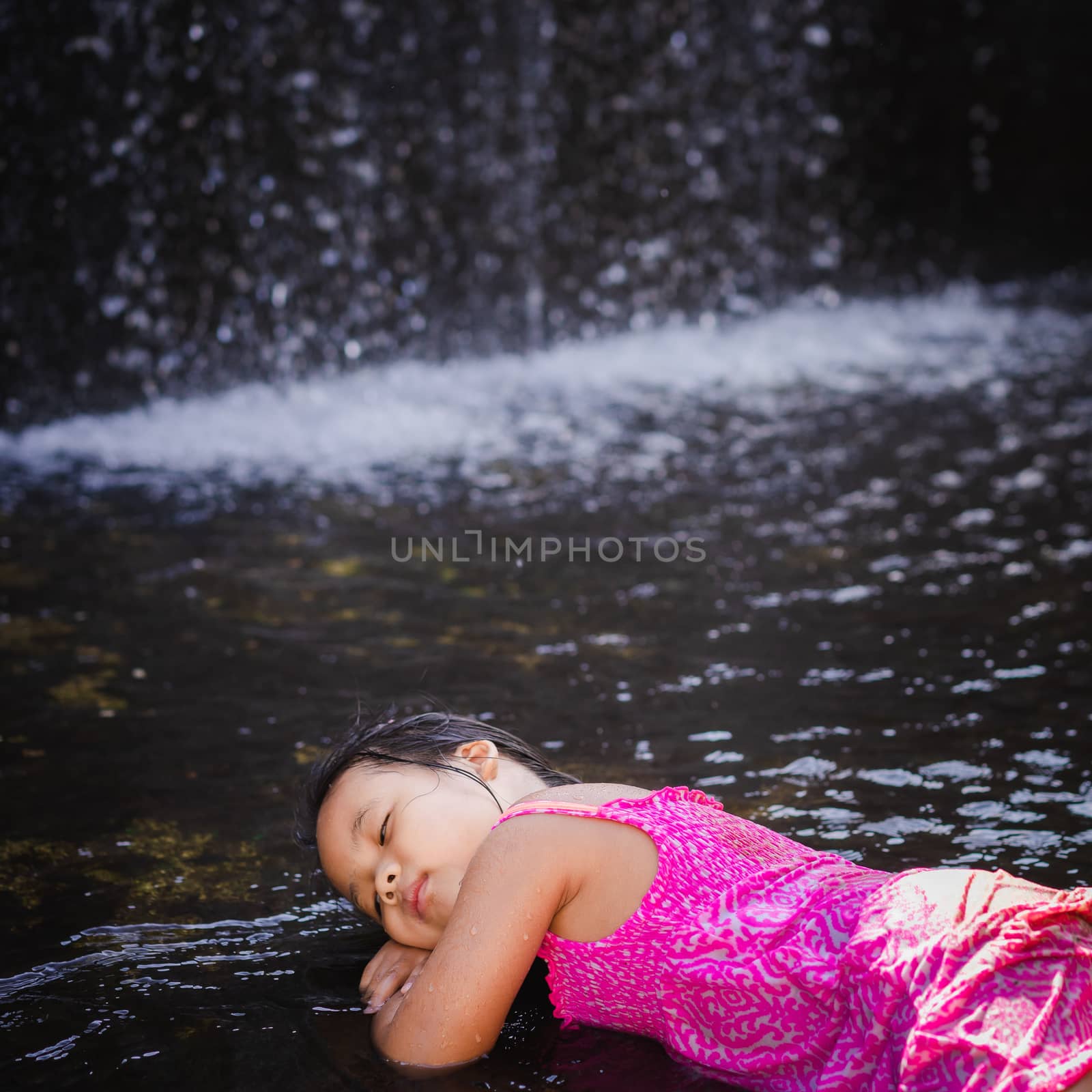 happy little asian girl sleeping near waterfall by domonite
