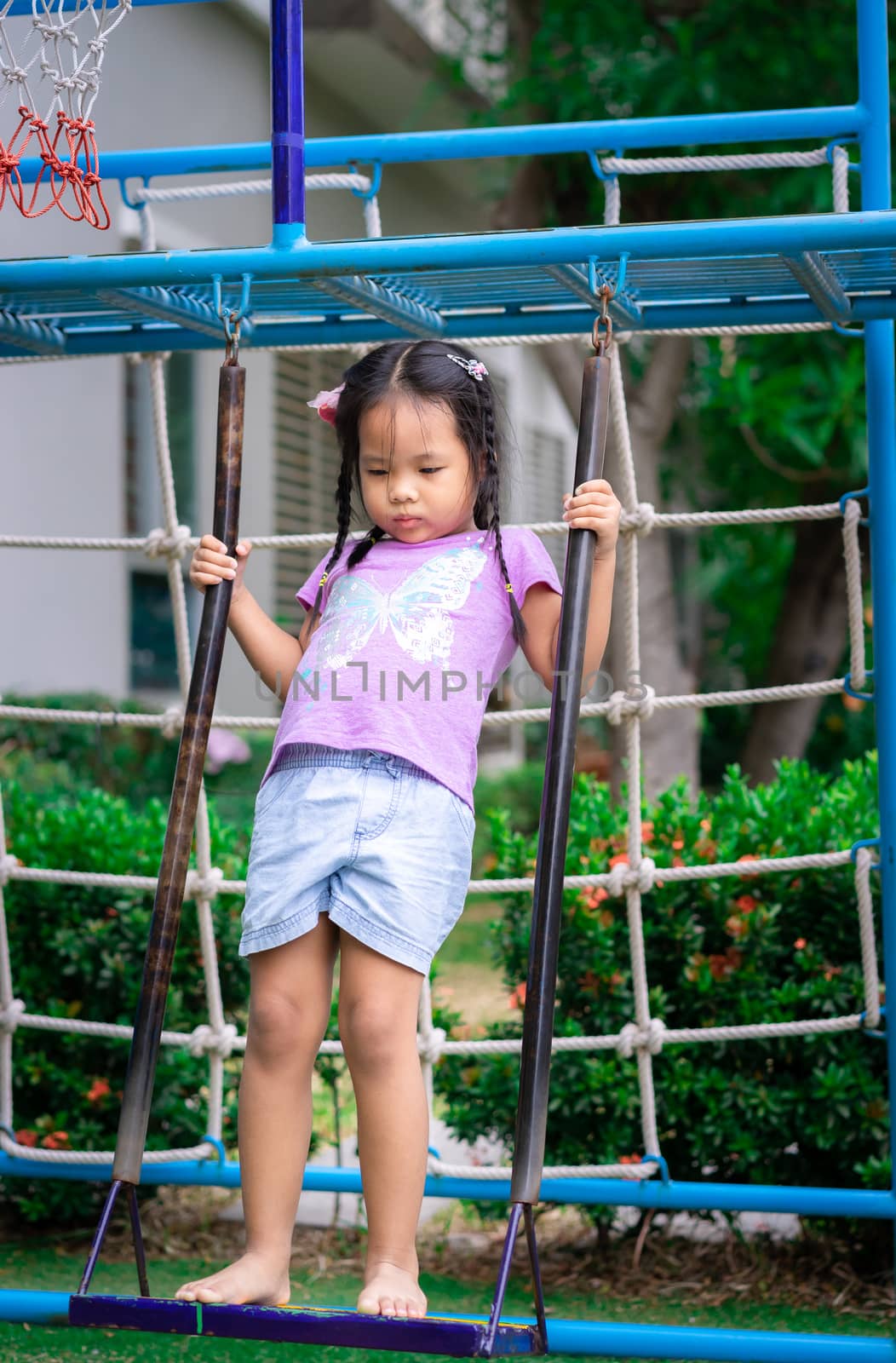 Little girl standing on a swing in the park