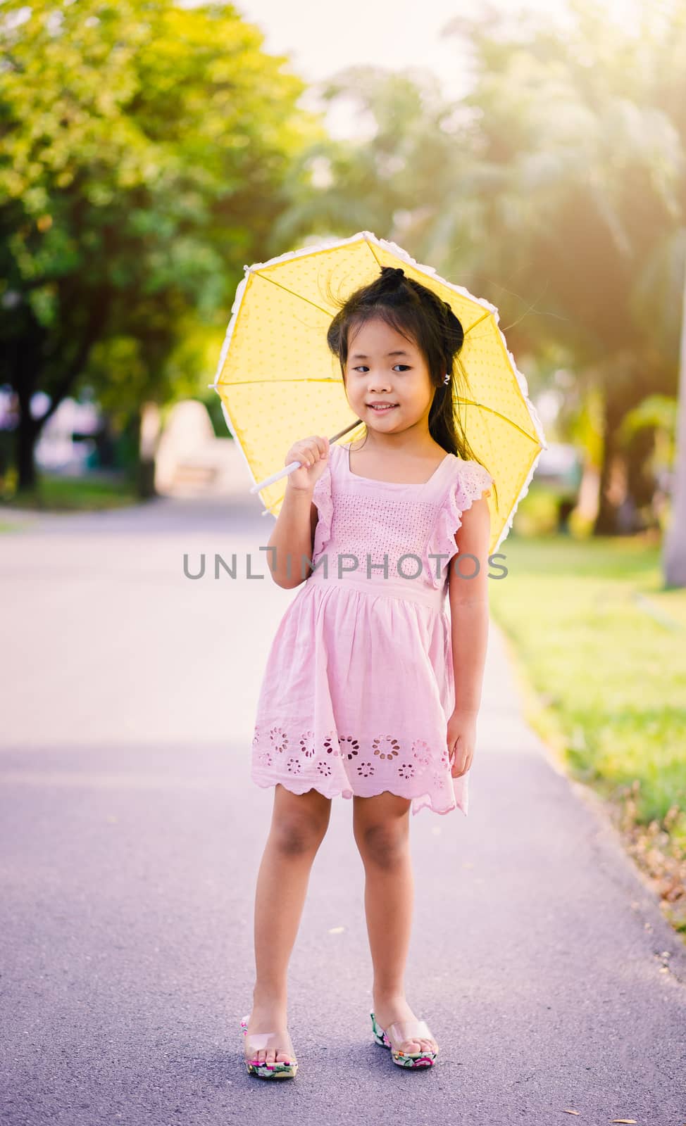 little girl in pink dress with yellow umbrella in sunny day