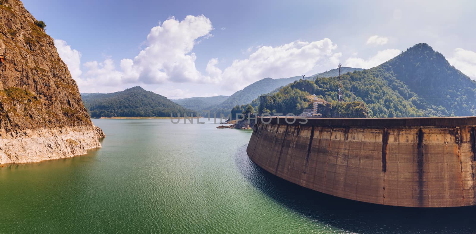 Summer scenery of Vidraru Dam and lake glowing in sunlight. Vidraru Dam, Romania. Carpathian Mountains, Fagaras ridge.