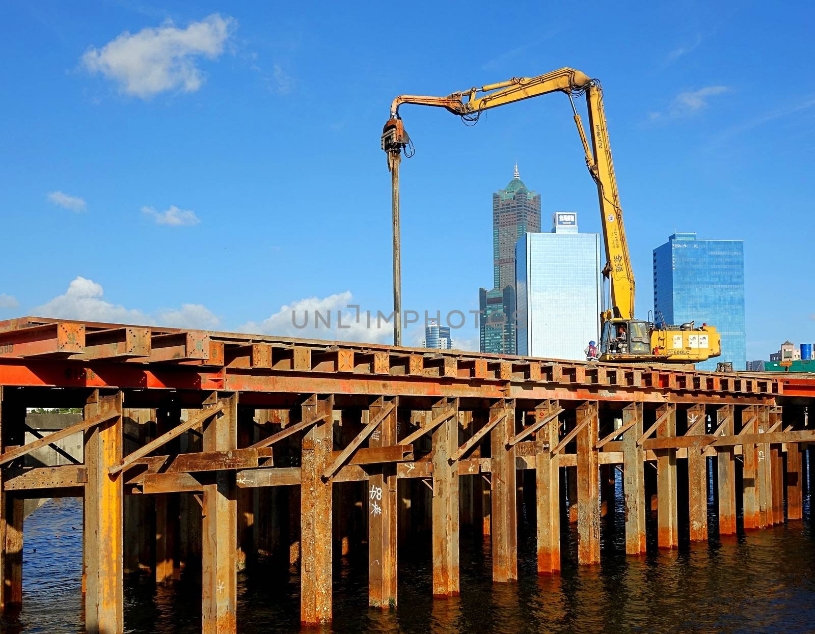 KAOHSIUNG, TAIWAN -- JUNE 14, 2015: An excavator drives a pile into the river bed as construction of a new bridge across the Love River continues.