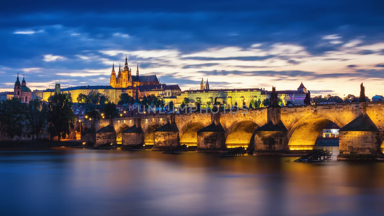 Prague Castle and the Charles Bridge at sunset in Prague, Czech Republic, Vltava river in foreground