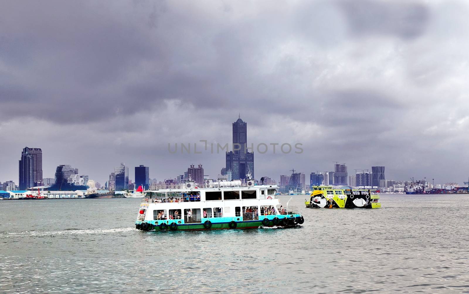 KAOHSIUNG, TAIWAN -- JUNE 30, 2018: The old and the new cross-harbor ferries pass by each other under a gloomy dark sky.
