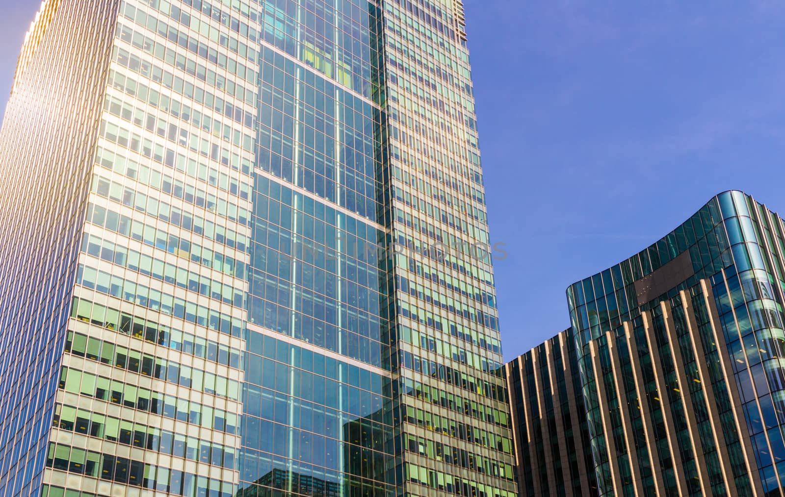 Bottom view of modern skyscrapers in business district against blue sky