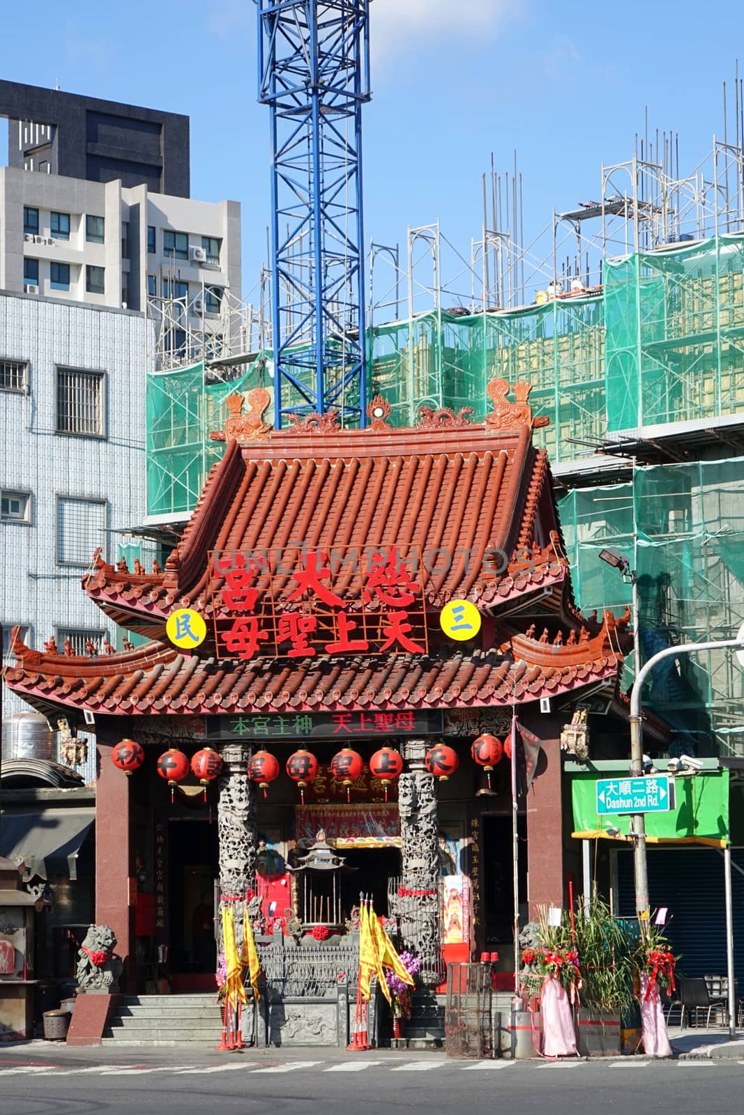 KAOHSIUNG, TAIWAN -- MAY 15, 2015: Old and New -- New building construction towers over the traditional Tsi Tian Temple in Kaohsiung City.