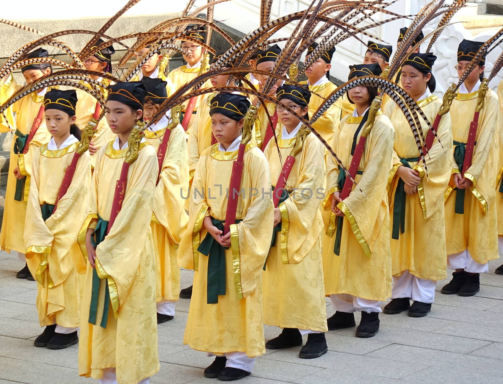 KAOHSIUNG, TAIWAN -- SEPTEMBER 28 , 2017: Young students in yellow robes carry peacock feathers during the yearly Confucius Ceremony held on Teachers Day.
