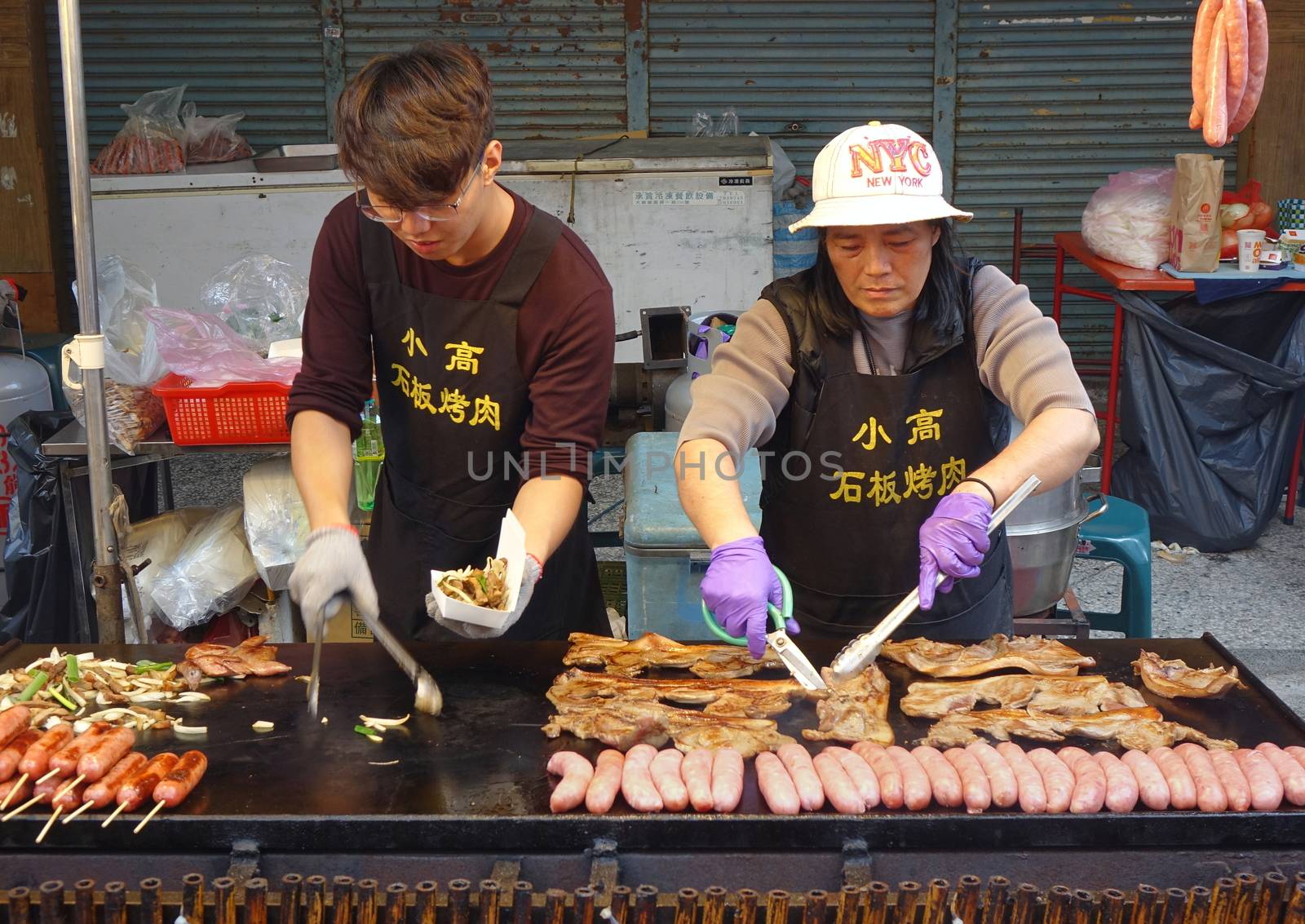 KAOHSIUNG, TAIWAN -- FEBRUARY 6, 2019: A street vendor cooks sausages, fried pork and onions in Teppanyaki style.
