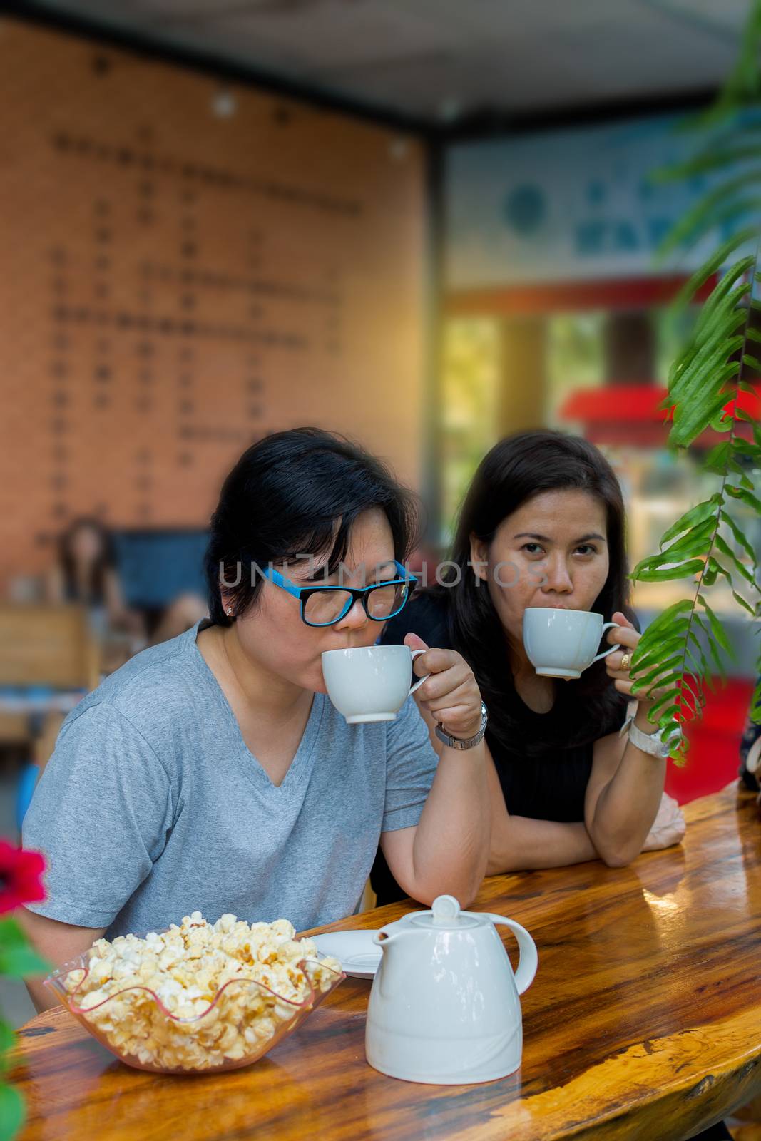 Best friends beautiful asian women drinking coffee and tea with popcorn have a friendship in talking and chatting in cafe coffee shop