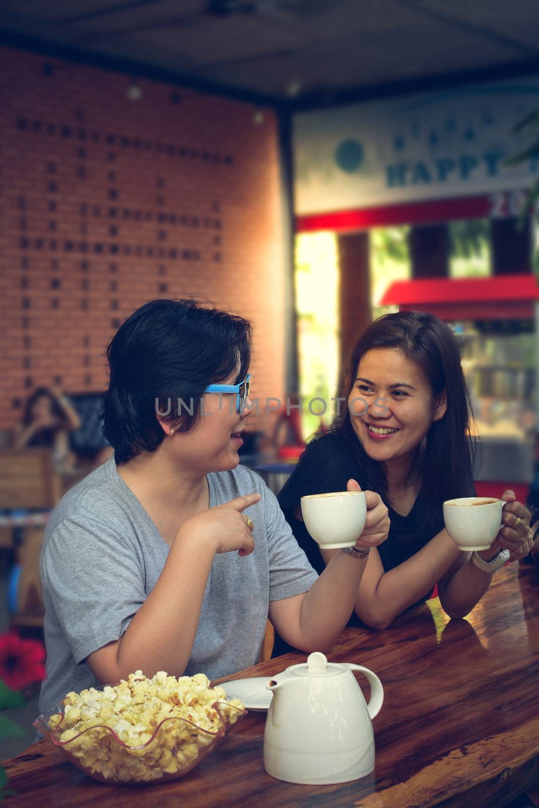 Best friends beautiful asian women drinking coffee and tea with popcorn have a friendship in talking and chatting in cafe coffee shop , process in vintage style