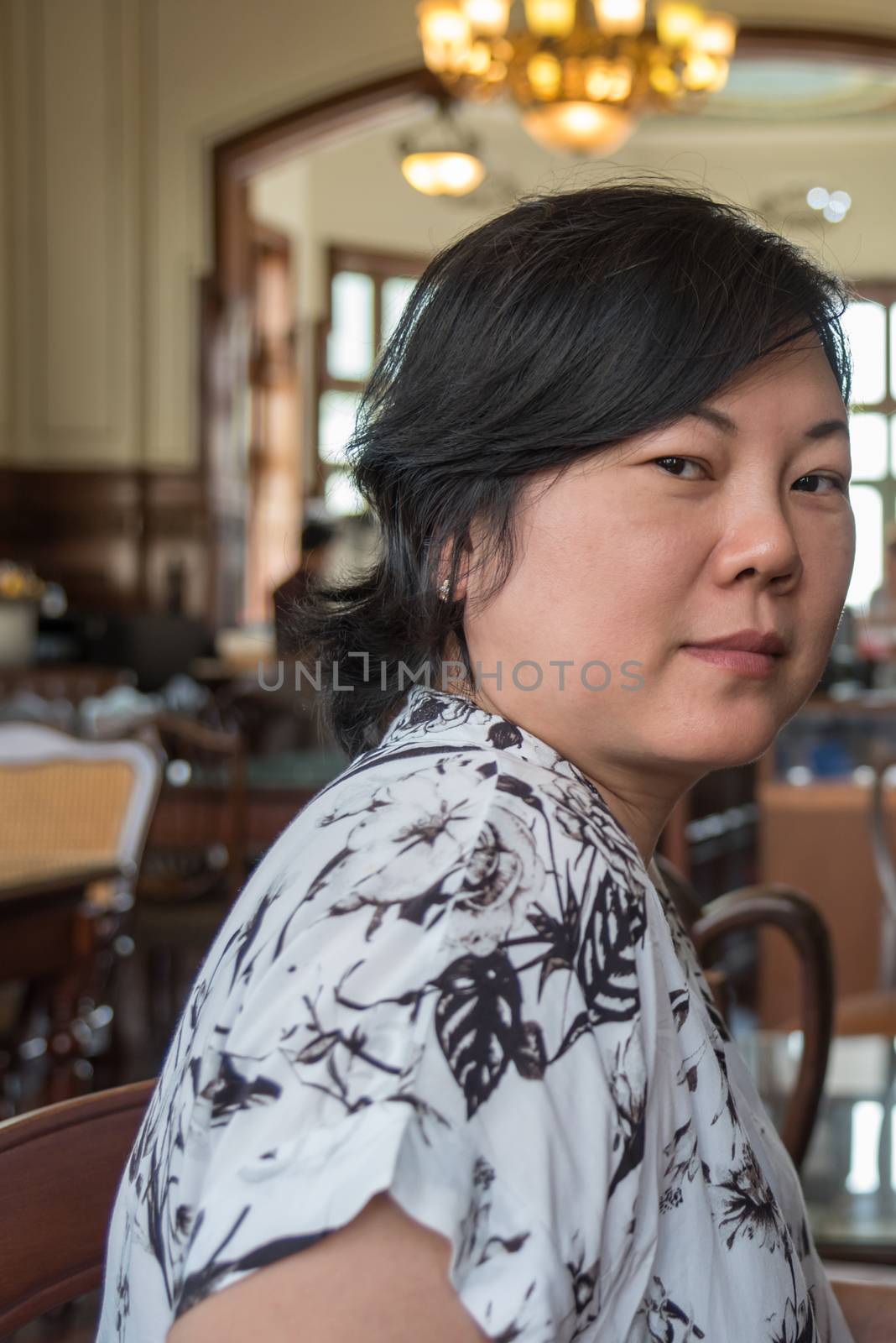 Asia women 40s white skin in white and black dress have a lovely smart smile gesture in a coffee shop cafe vintage style