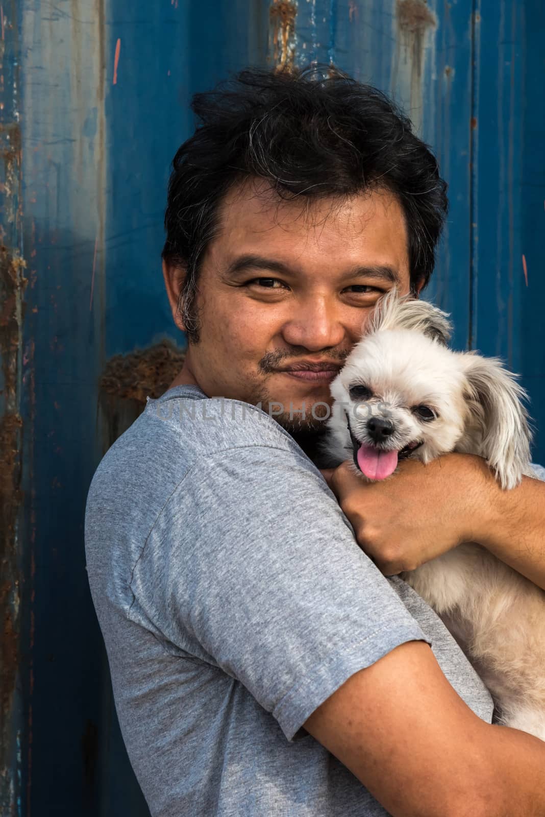 Asia man and dog happy smile hugging her pat is a dog so cute mixed breed with Shih-Tzu, Pomeranian and Poodle with rusty blue industry container background