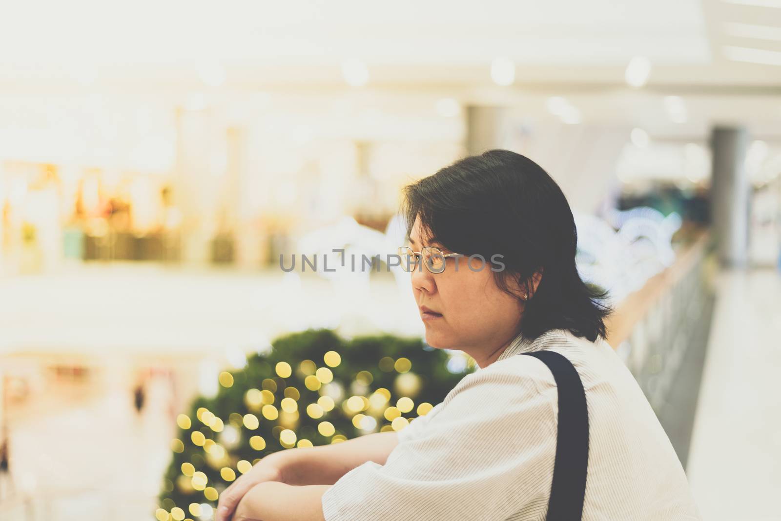 Asian woman 40s white skin plump body with backpack waiting in department store or shopping mall with pine tree in merry christmas and new year celebration